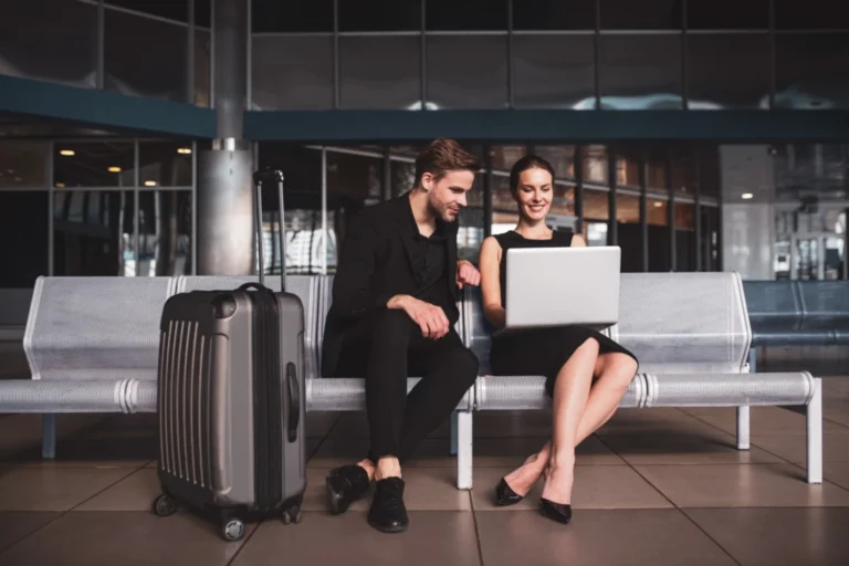 Viajeros corporativos gestionando gastos de viaje y viáticos con herramientas digitales mientras esperan su vuelo.
