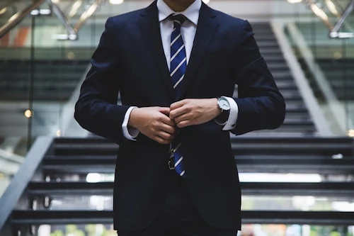 Ejecutivo ajustando su traje, representando la importancia de una buena planificación y un itinerario de viaje de negocios bien estructurado.