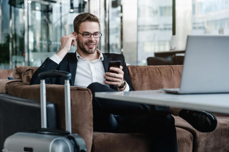 Profesional sonriendo mientras usa su móvil, reflejando una experiencia optimizada en la gestión de viajes de negocios a través de soluciones digitales.